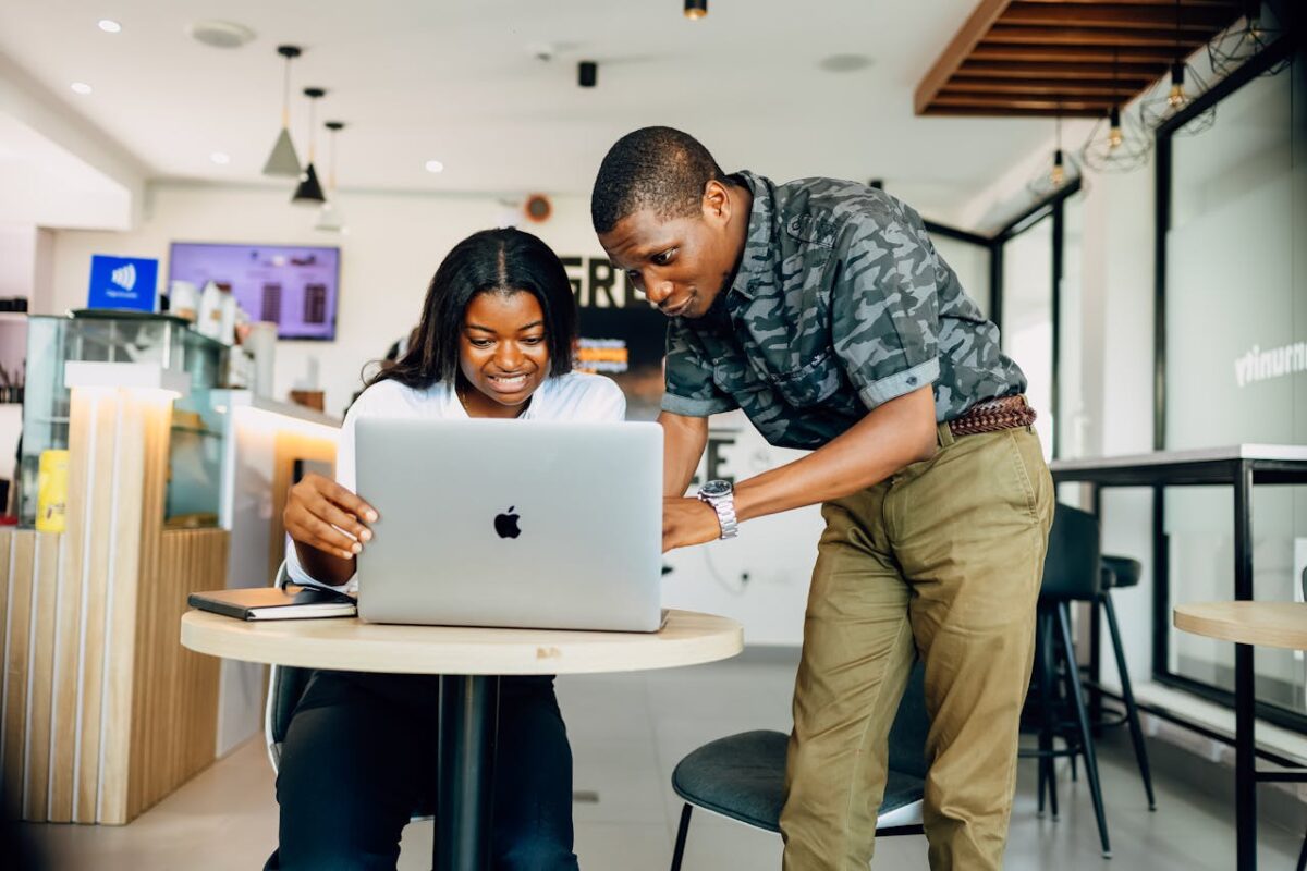 A team collaborates in a Lagos café, using a laptop for a modern work project.