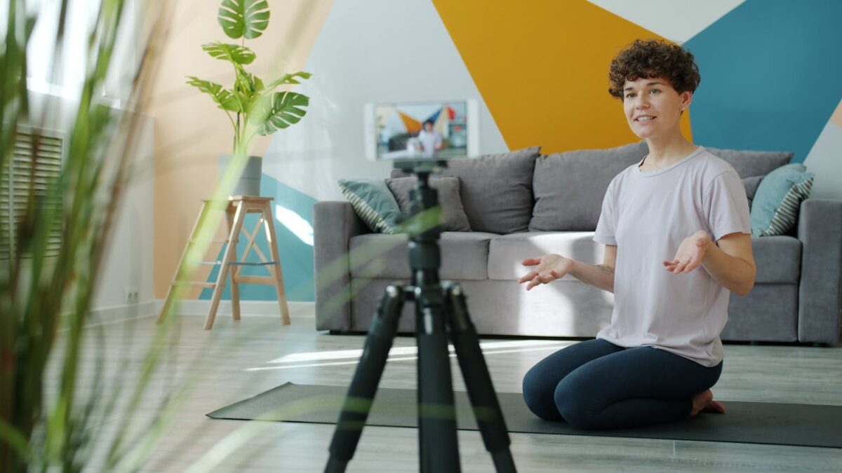 A woman recording a yoga session in a bright, modern living room setting.